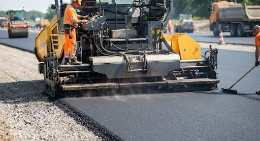 Asphalt paver and crew laying a fresh road surface